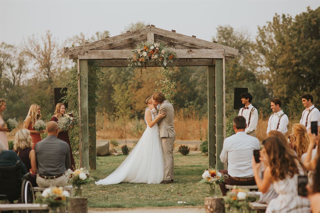 A ceremony under the weathered-wood arbor with autumn florals
